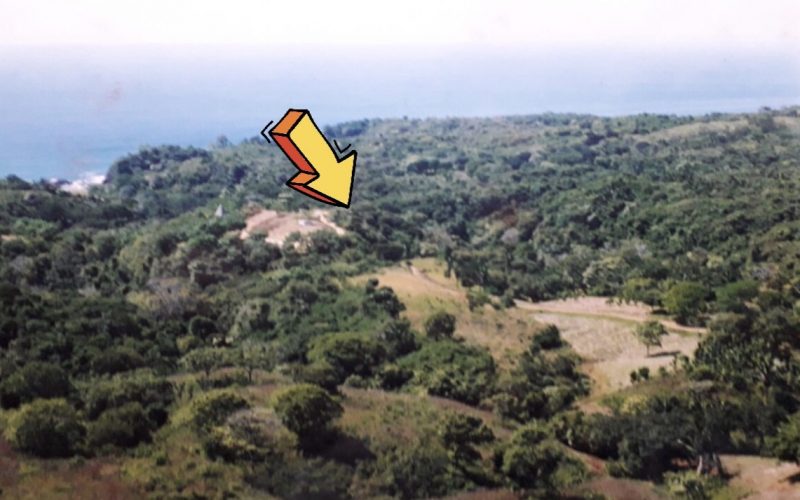Luftaufnahme eines Baugrundstücks bei Ostional mit Pfeilmarkierung, umgeben von dichter Vegetation und Blick auf das Meer.