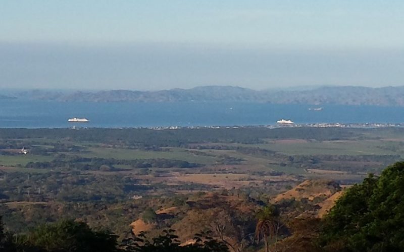 Blick auf die Küstenlandschaft bei Miramar mit zwei Kreuzfahrtschiffen auf dem Meer.