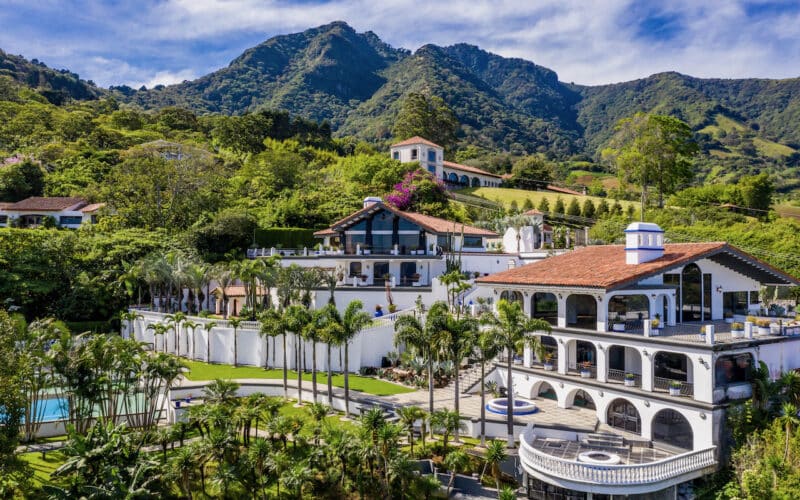 Villa in Escazu mit üppiger Vegetation und Bergen im Hintergrund.