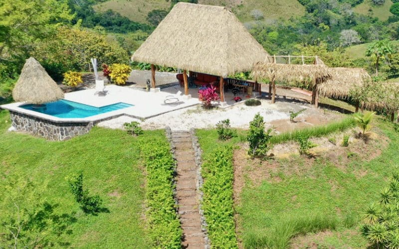 Außergewöhnliche Liegenschaft in Playa Coyote mit Pool und Palapa, umgeben von grüner Landschaft.
