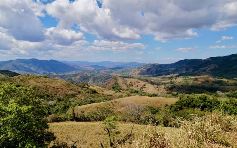 Hügellandschaft auf der Nicoya Halbinsel mit bewölktem Himmel und grüner Vegetation.