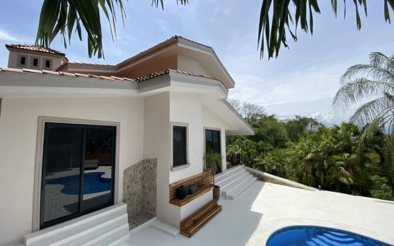 Schönes Haus mit Pool und Terrasse in Playa Naranjo, umgeben von Palmen.