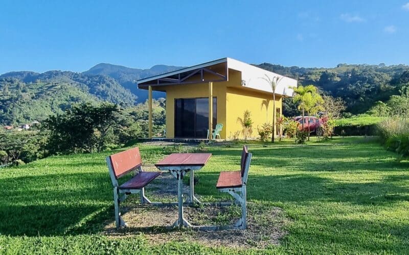 Gelbes Gebäude mit Terrasse und Gartenmöbeln vor Berglandschaft in El Castillo, Arenalsee.
