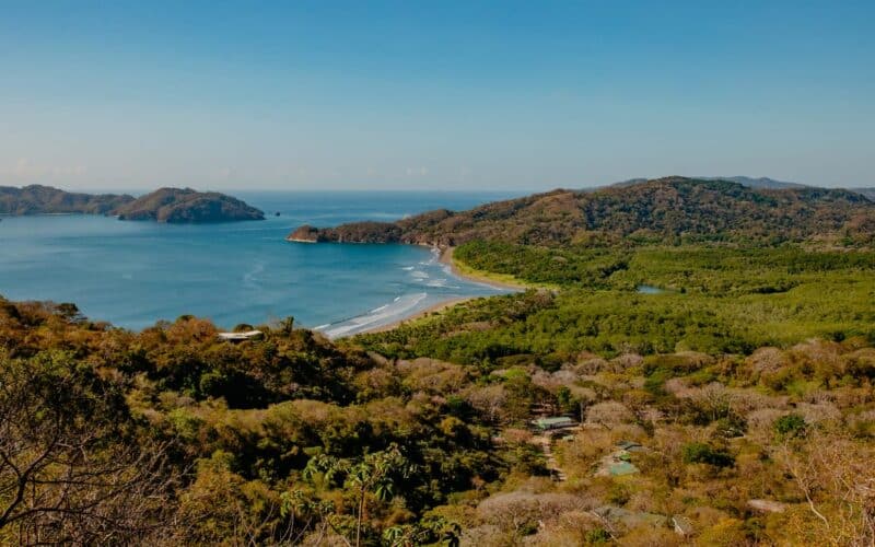 Blick auf die Küste von Playa Organos mit bewaldeten Hügeln und blauem Meer.