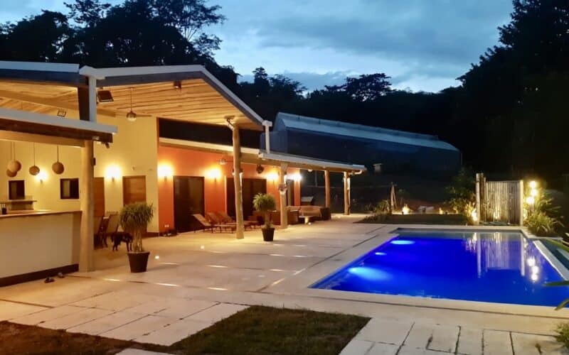 Moderne Finca bei Playa Naranjo mit Pool und beleuchteter Terrasse in der Abenddämmerung.