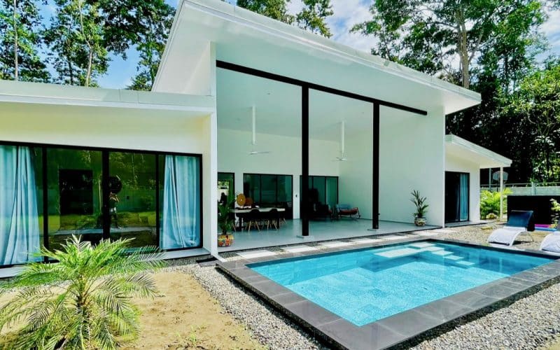 Modernes Haus mit Pool und Terrasse in Cahuita, umgeben von tropischen Bäumen.