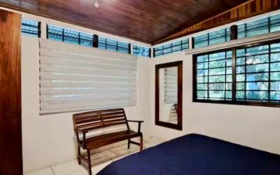 Schlafzimmer mit Holzdecke, Fensterläden, Spiegel und Holzbänken in der Liegenschaft an der Playa Tambor.