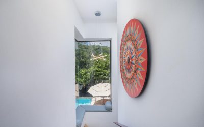 Treppenhaus mit großem Fenster, Blick auf den Pool und dekorativem Wandkunstwerk.