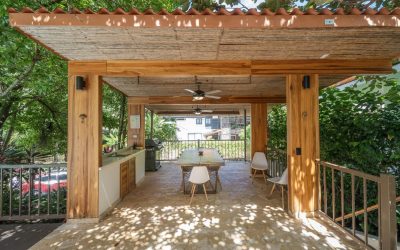 Überdachte Terrasse mit Holztisch und Stühlen in einer Villa bei Tamarindo, umgeben von üppigem Grün.