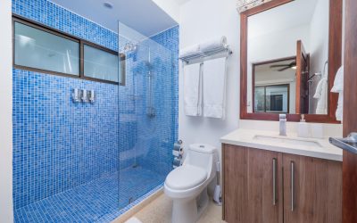 Modernes Badezimmer mit blauen Fliesen, Glasdusche und Holzwaschtisch in Villa bei Tamarindo.