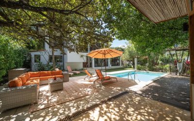 Terrasse einer Villa bei Tamarindo mit Pool, Sonnenschirm und Sitzbereich unter Bäumen.