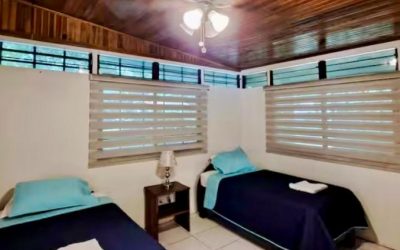 Schlafzimmer mit zwei Einzelbetten, Ventilator und Holzbalkendecke in einer Liegenschaft an der Playa Tambor.