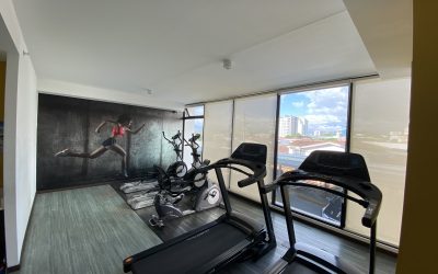 Fitnessraum mit Laufbändern und Blick auf die Stadt in einer Eigentumswohnung in Rohrmoser San Jose.