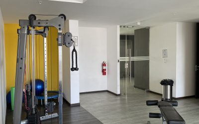 Fitnessraum mit Hanteln, Fitnessgeräten und einer Bank im 20. Stock eines Mietobjekts in Rohrmoser San Jose.