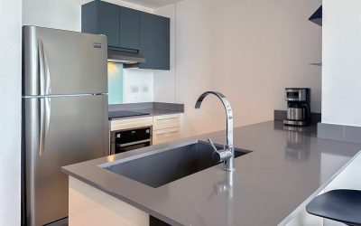 Moderne Küche mit Edelstahlkühlschrank, Herd, Spüle und Kaffeemaschine in einer Eigentumswohnung in Rohrmoser San Jose.
