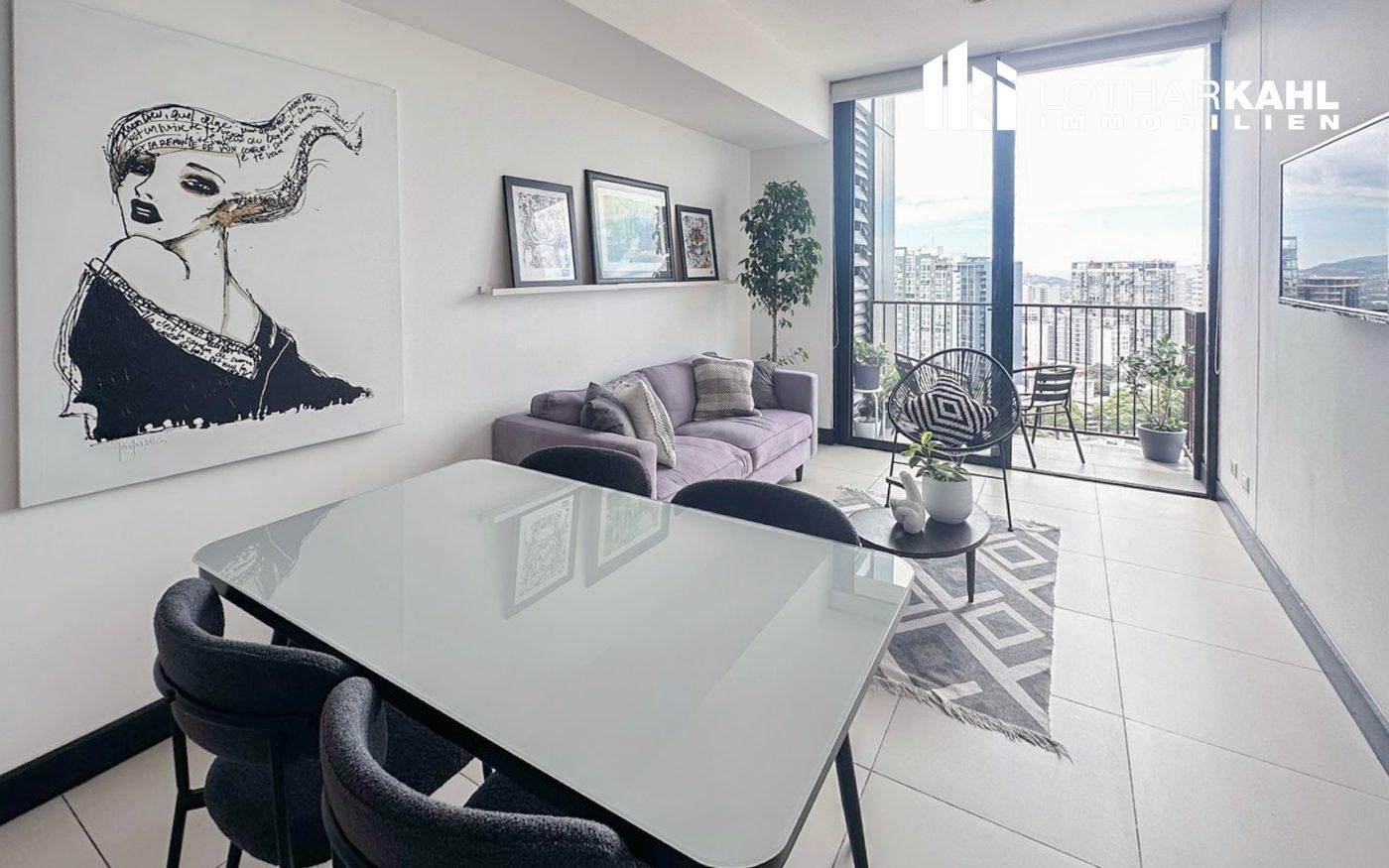 Wohnzimmer einer Eigentumswohnung im 20. Stock in Rohrmoser San Jose mit moderner Einrichtung und Balkonblick.