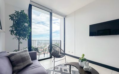 Wohnzimmer einer Eigentumswohnung im 20. Stock in Rohrmoser San Jose mit großem Fenster und Balkonblick.