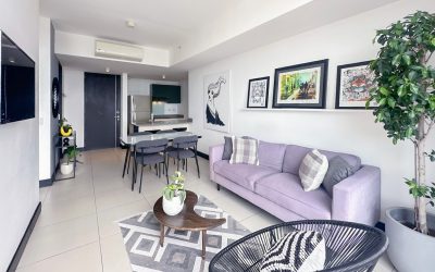Modernes Wohnzimmer mit lila Sofa, Esstisch und Kunstwerken an der Wand in einer Eigentumswohnung in Rohrmoser San Jose.