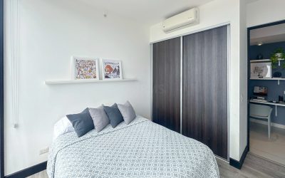 Schlafzimmer mit Doppelbett, grauen Kissen und Holzeinbauschrank in einer Eigentumswohnung in Rohrmoser San Jose.