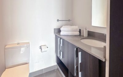 Modernes Badezimmer mit Toilette, Waschbecken und dunklem Waschtisch in einer Eigentumswohnung in Rohrmoser San Jose.